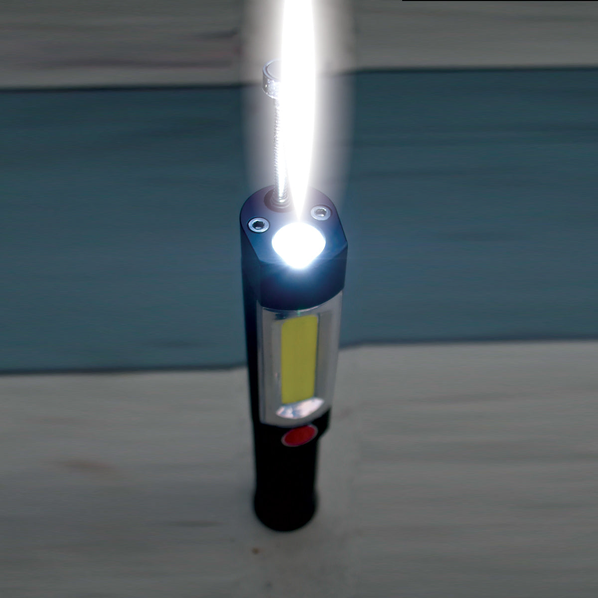 Handheld flashlight emitting light on a neutral background