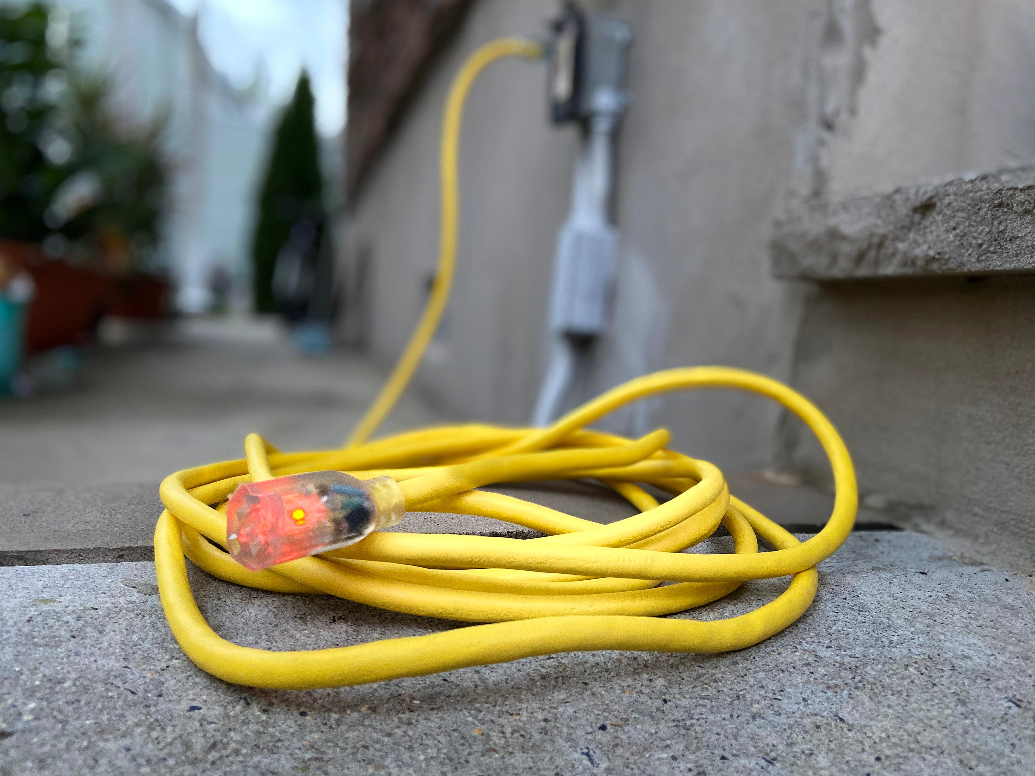 yellow extension cord coiled on a sidewalk