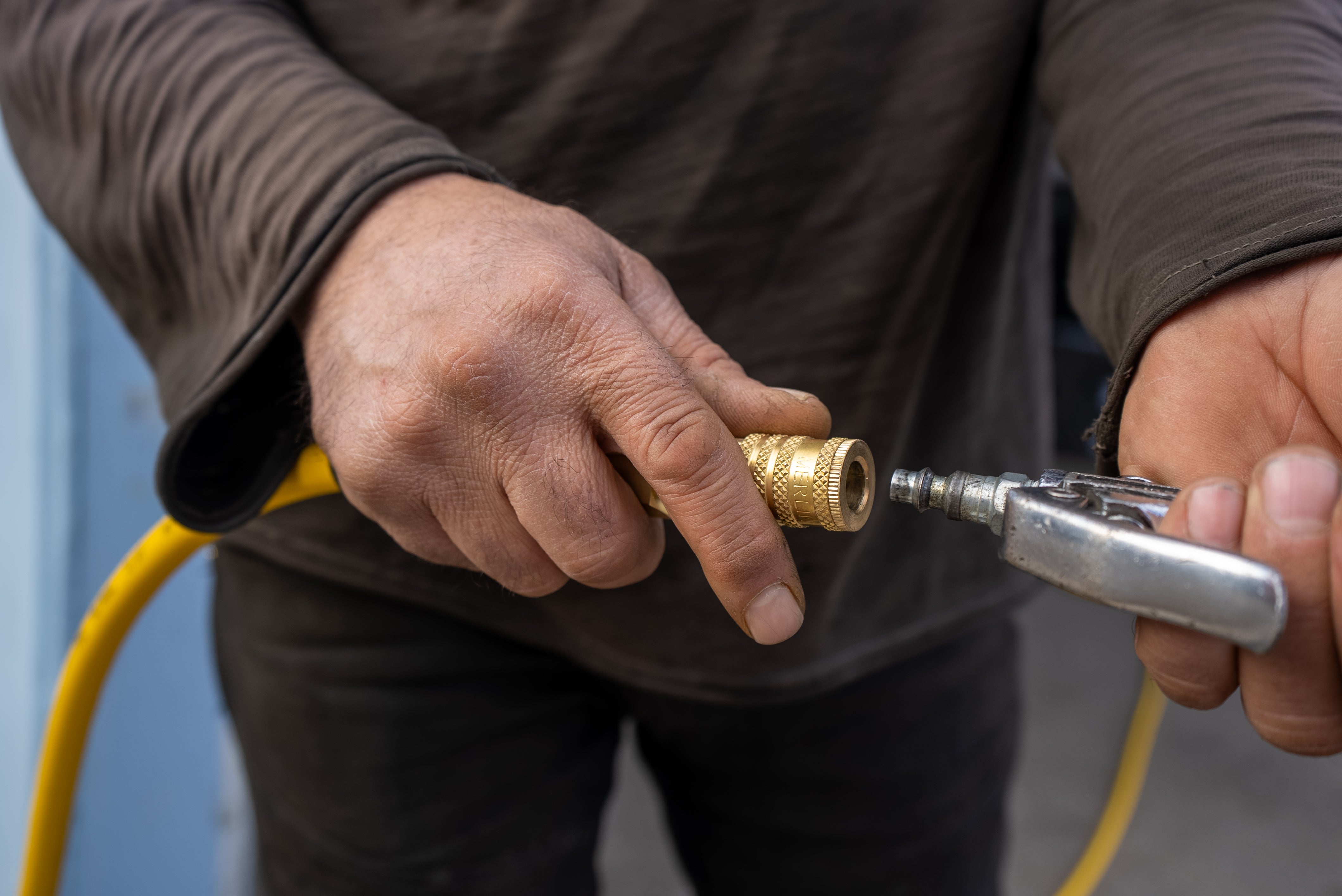man plugging in air compressor to pvc air hose
